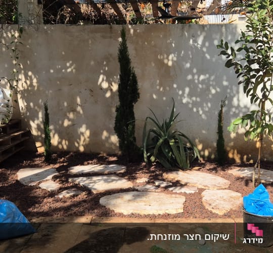 עיצוב פינת גינה עם אבני מדרך, חיפוי טוף ושתילת עצים